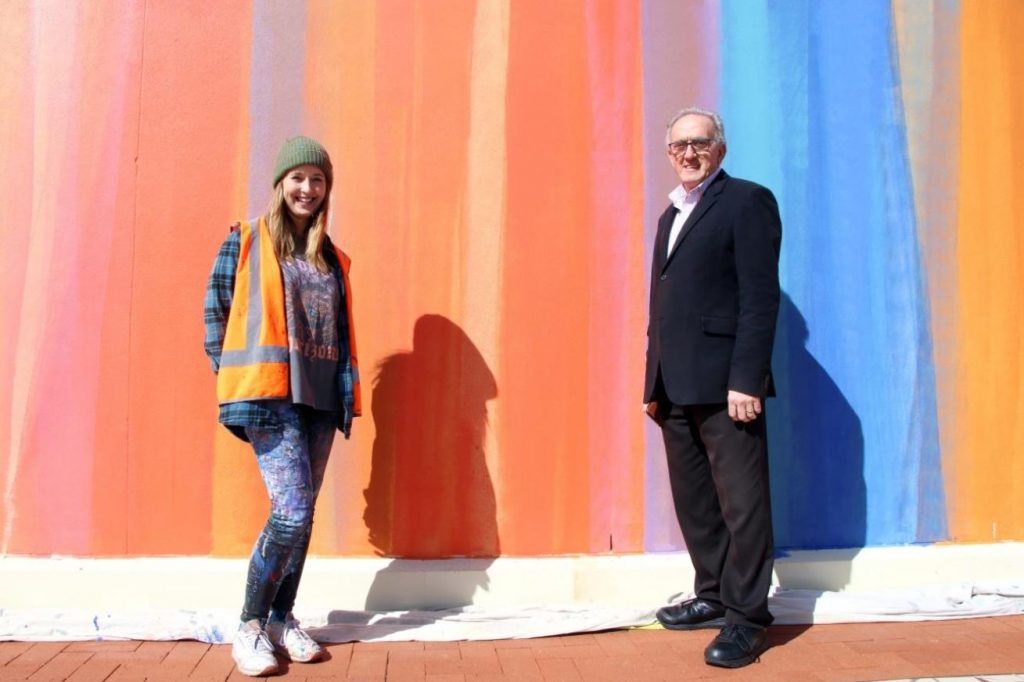 Image: Artist, Claire Foxton, and Chair of the Public Art Committee, Cr Anthony Michael, are pictured in front of the, now colourful, canvas in Evans Street.