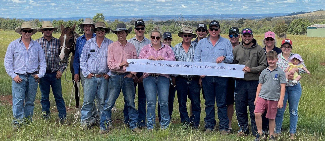 Members of the polocrosse club are pictured holding up a banner that reads "With thanks to the Sapphire Wind Farm Community Fund". 