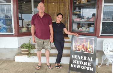 Pictured are Daryl and Jenny Boyd holding hands out the front of their newly opened store in Martyn Street Ashford, TnJ Store, with a sandwich board sign that reads "general store now open". 
